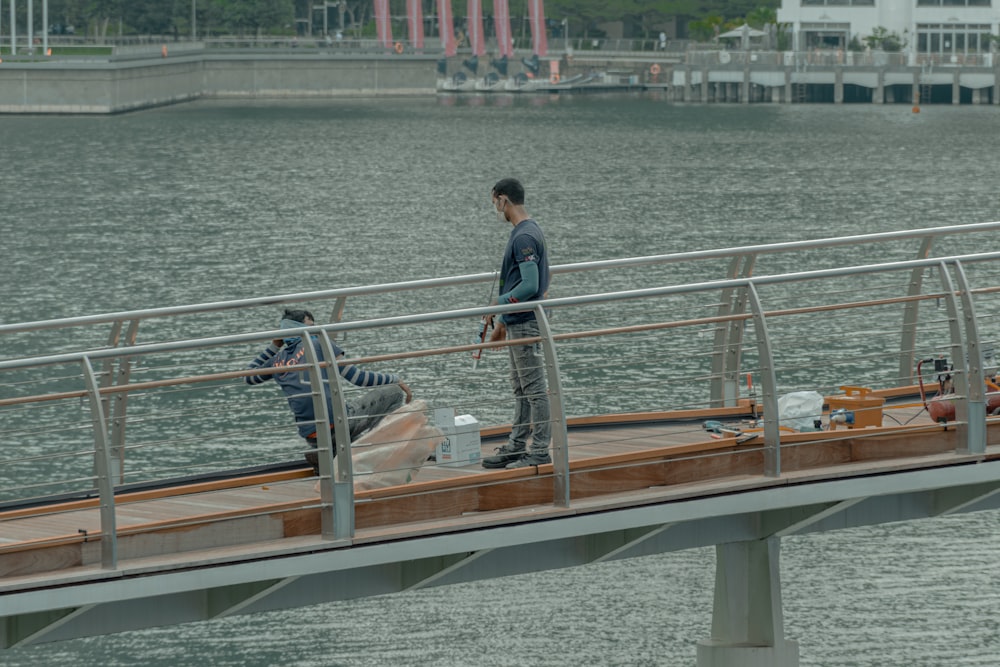 man in blue denim jacket standing on brown wooden dock during daytime