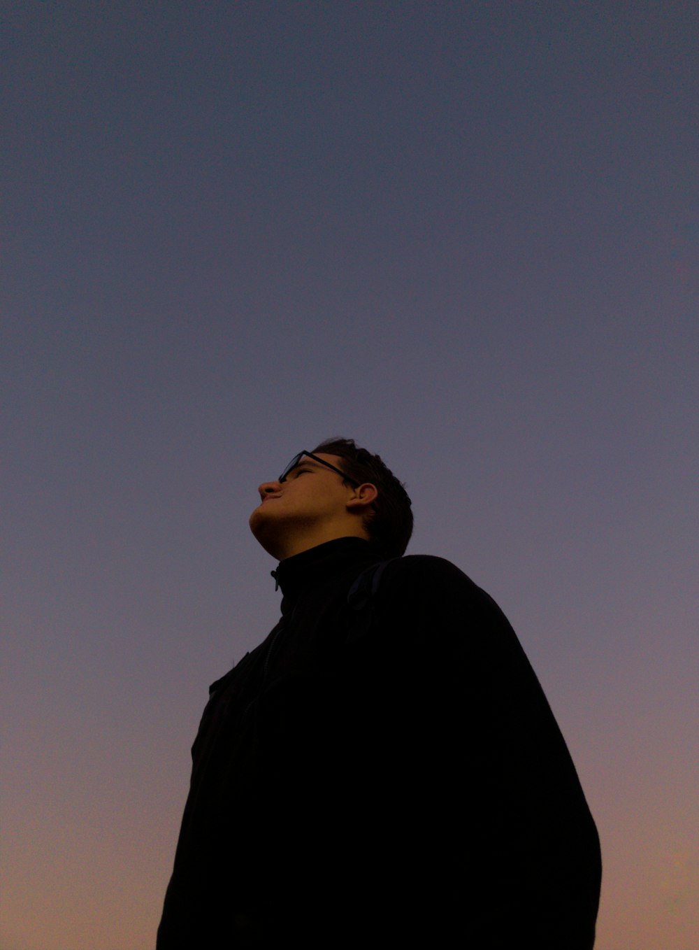 uomo in giacca nera in piedi durante il tramonto