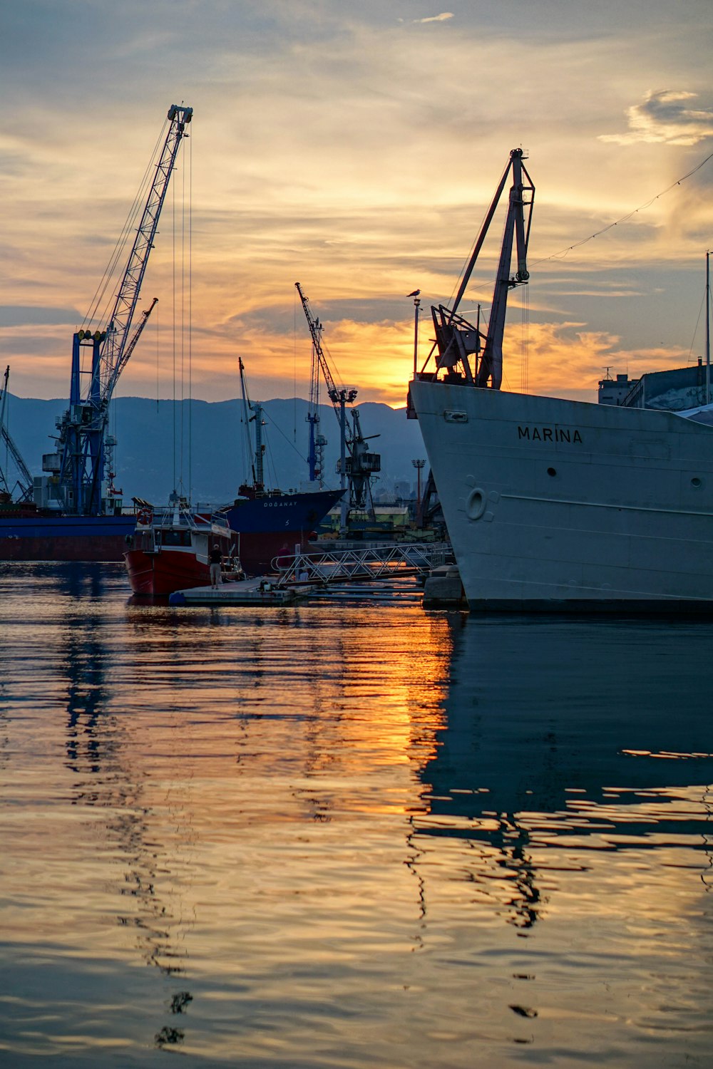 Bateau blanc et rouge sur le plan d’eau au coucher du soleil