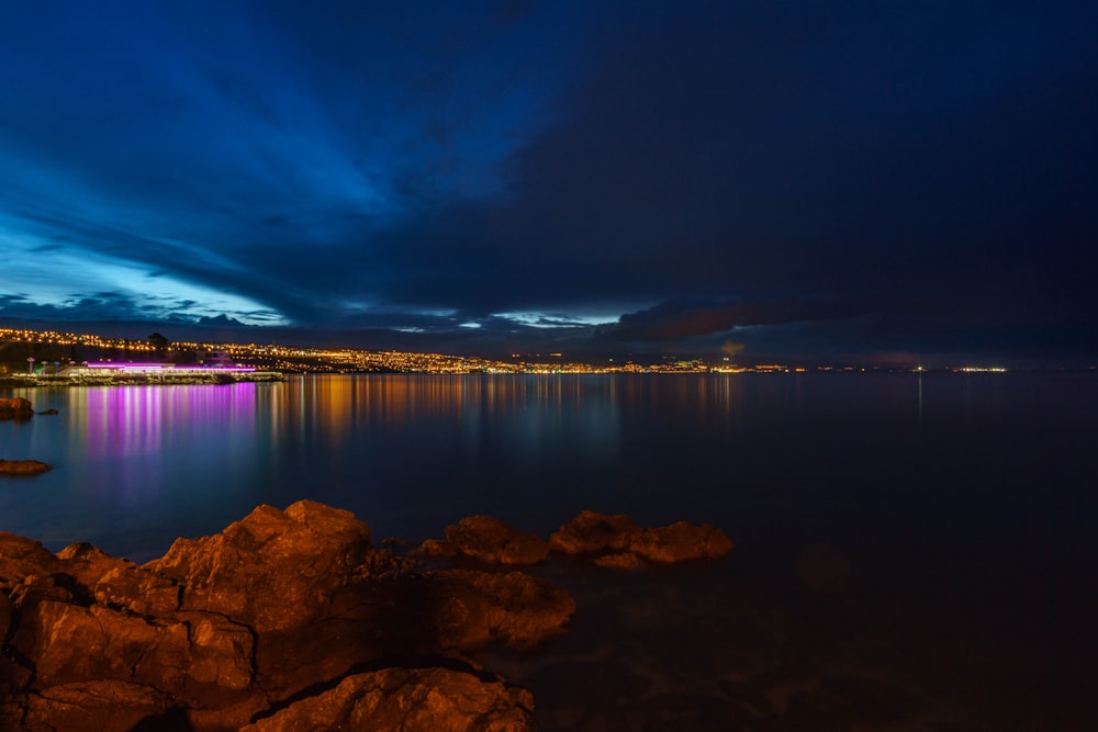 body of water near mountain during night time