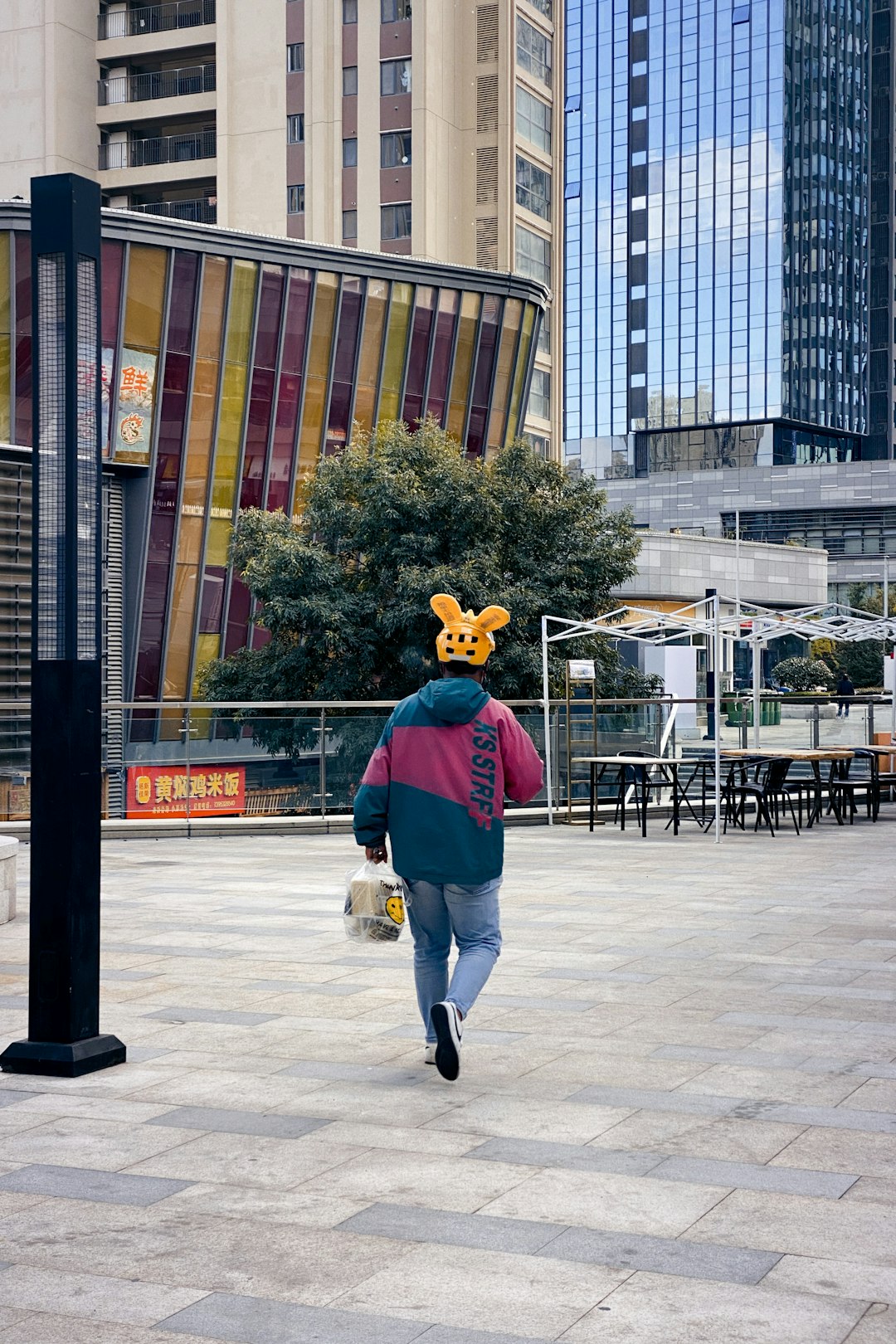 man in blue and orange mickey mouse hoodie walking on sidewalk during daytime