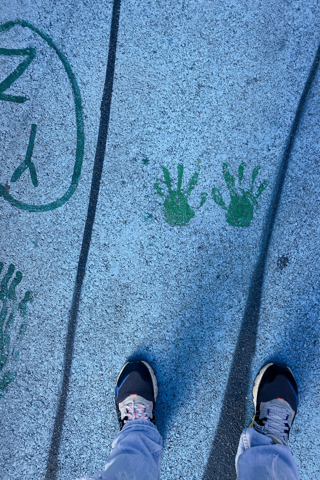 person in black rubber clogs standing on gray concrete pavement