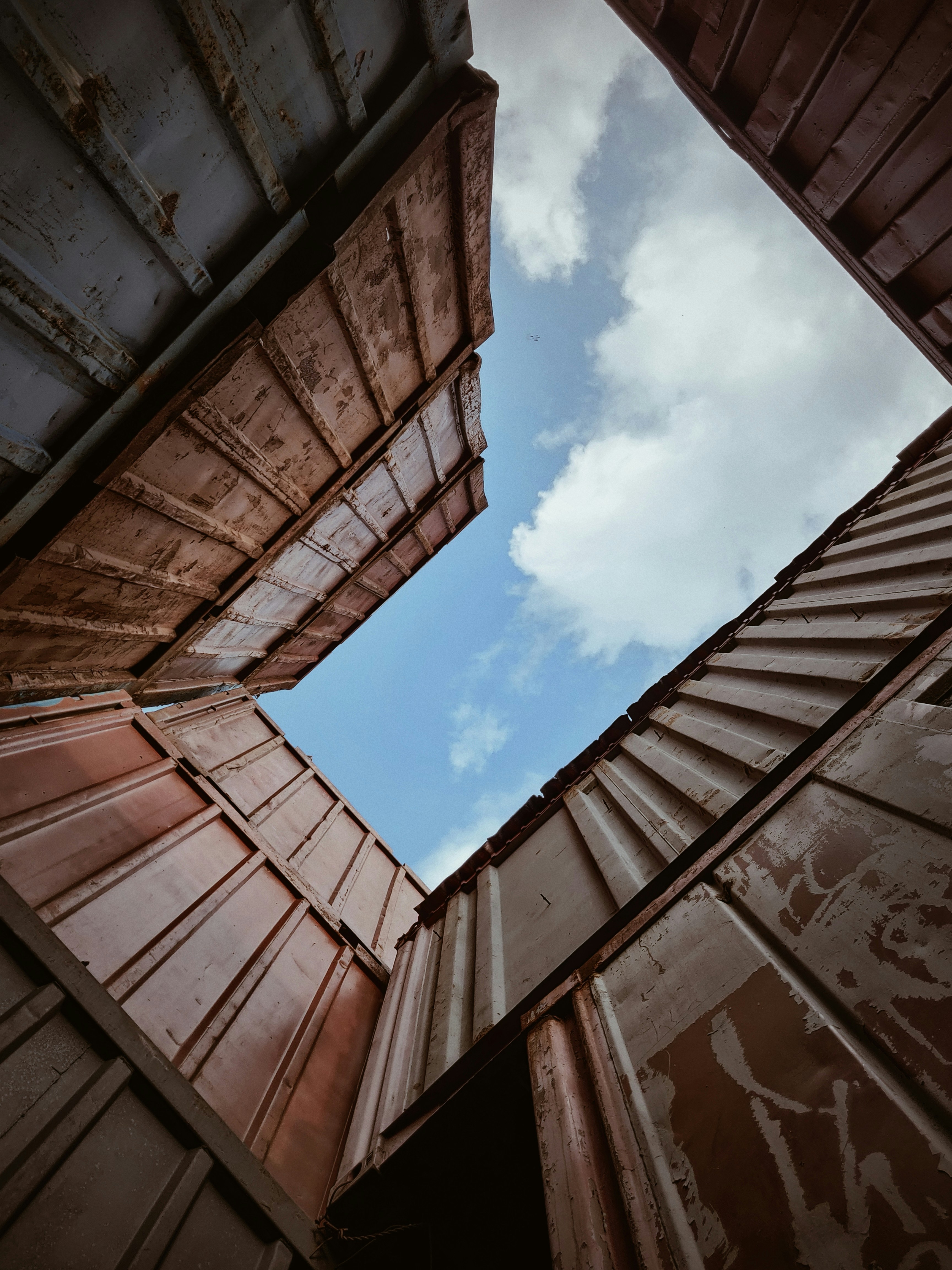 Looking upwards at the sky in a maze of ocean containers.