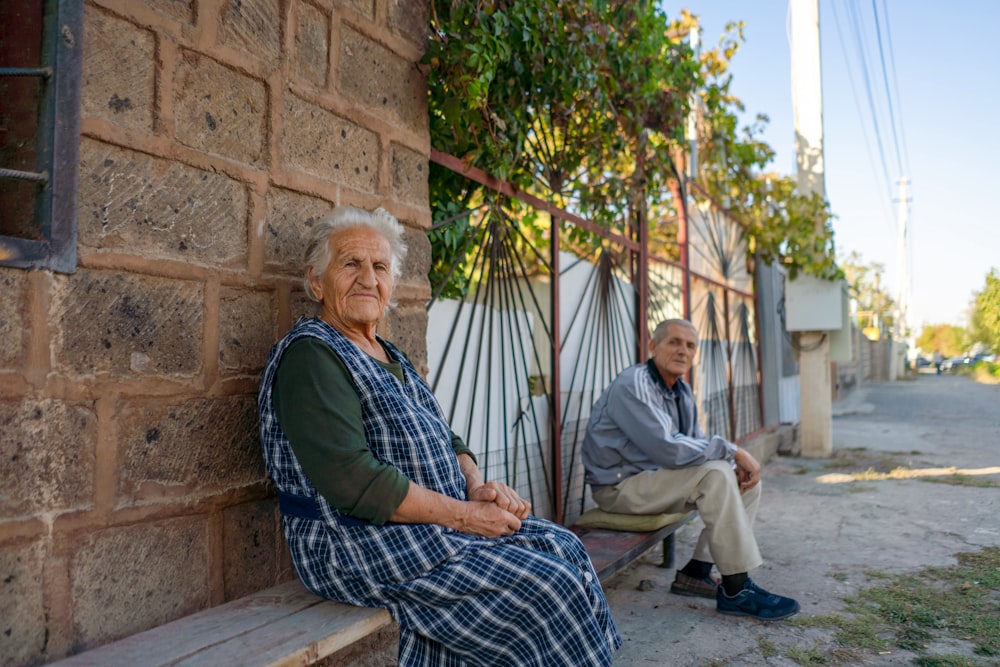 Un par de personas sentadas en un banco al lado de un edificio