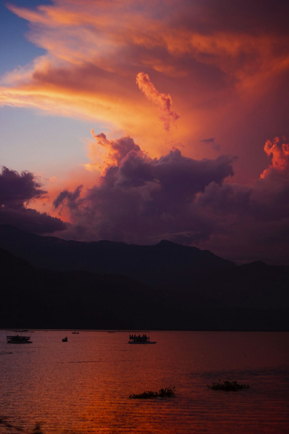 a group of boats floating on top of a lake under a cloudy sky