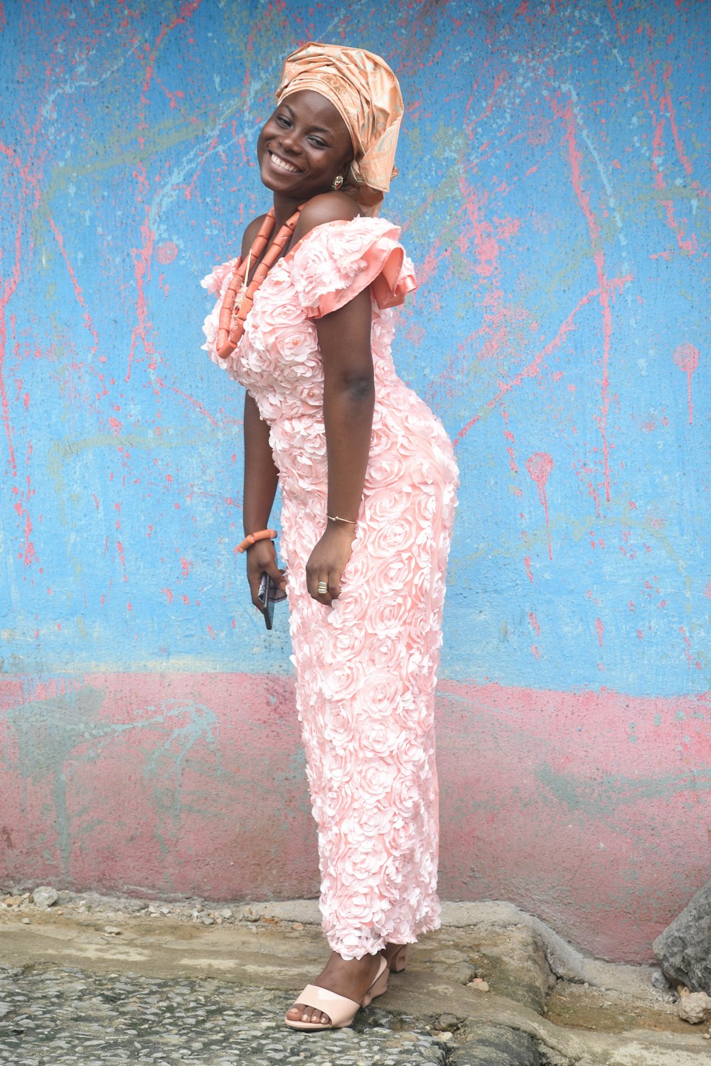 woman in white and brown floral dress standing beside blue wall