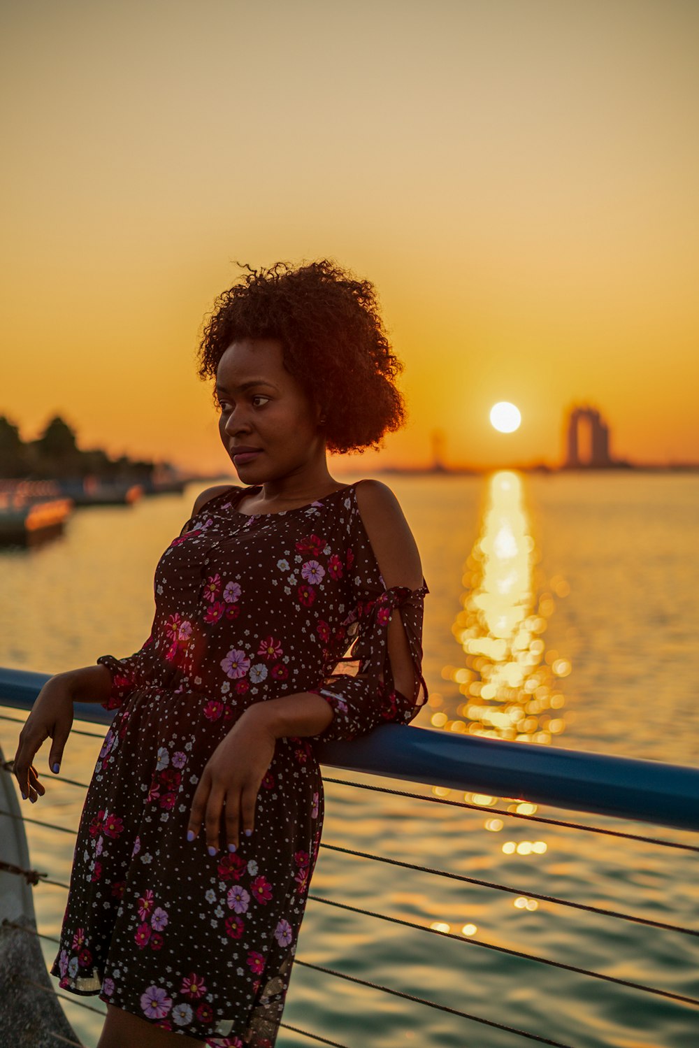 a woman is standing on a dock at sunset