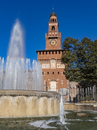 brown concrete building near water fountain during daytime