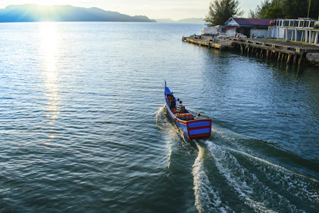 Passengers enjoying a calm boat ride with vibrant local scenery in the background.