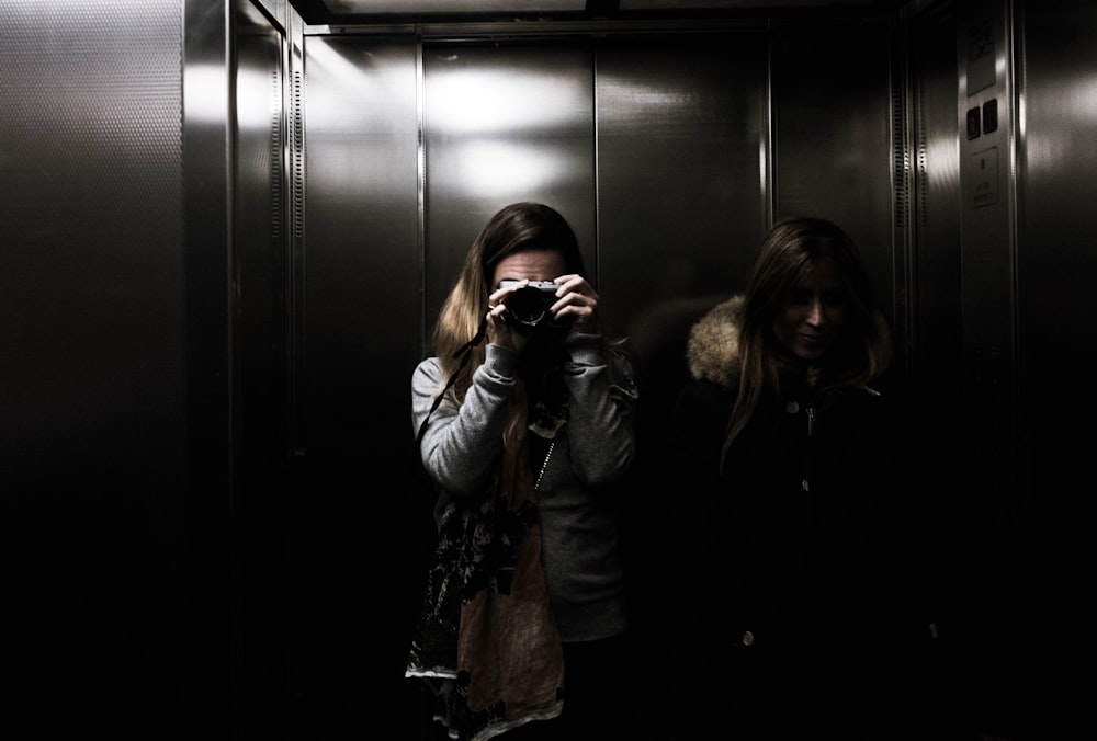 woman in black jacket holding black dslr camera