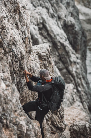 A person wearing high-tech clothing climbing a rugged mountain trail at sunrise.