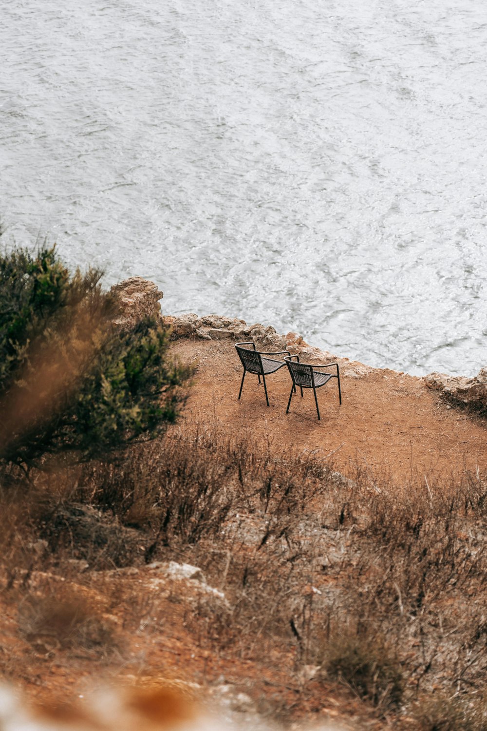 brown wooden chair on brown grass near body of water during daytime