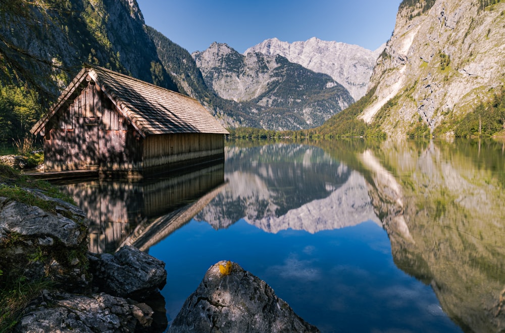 brown wooden house on rocky mountain beside lake during daytime