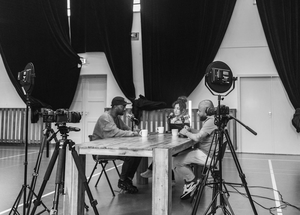 grayscale photo of 2 men sitting on chair in front of table