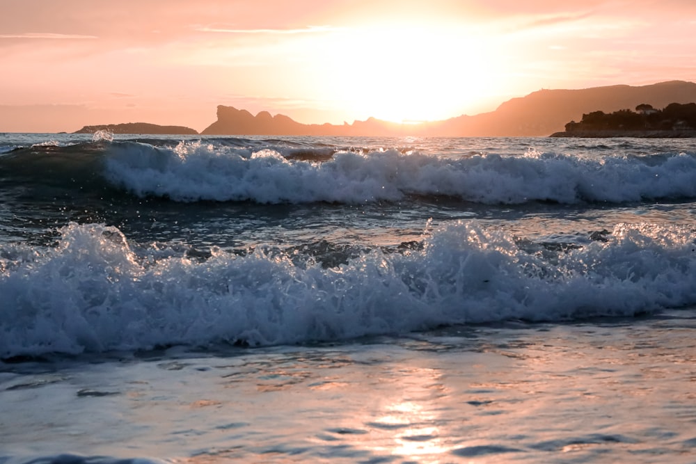 ocean waves crashing on shore during sunset