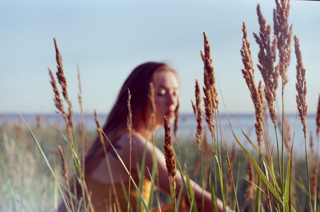 woman in yellow tank top sitting on green grass field during daytime