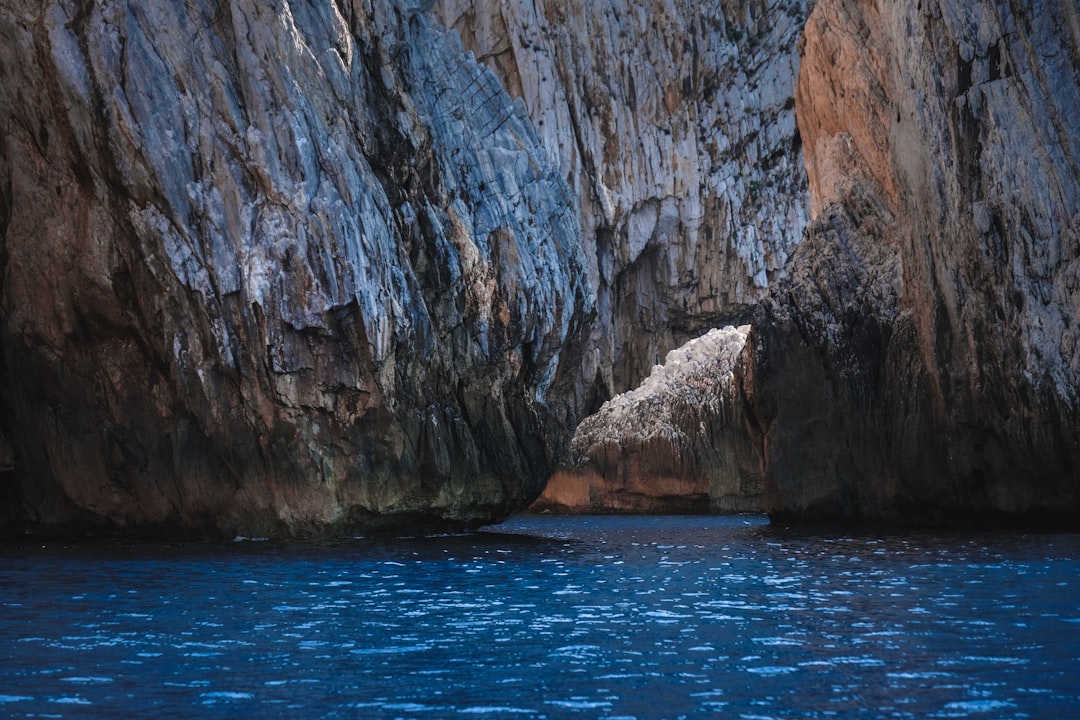 brown rocky mountain beside blue sea during daytime