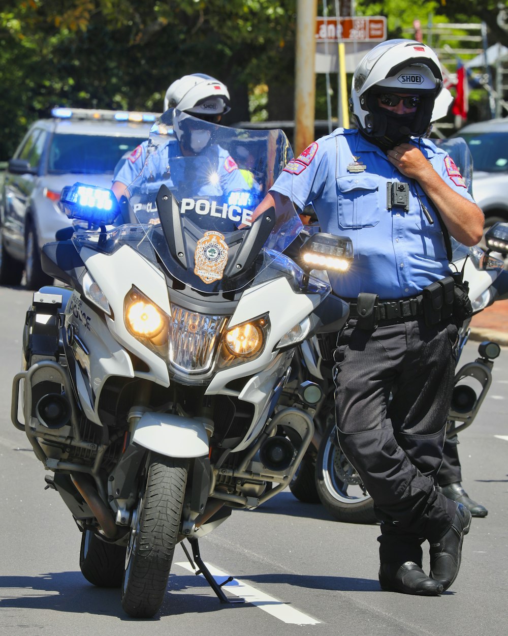 uomo in tuta da poliziotto blu e bianca che guida su una motocicletta blu e bianca durante il giorno