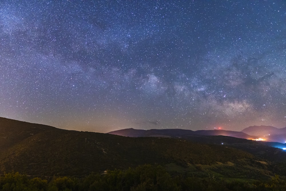 夜の星空と青空の下の山のシルエット