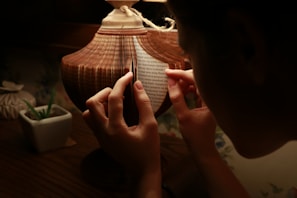 Artisan carefully inspecting a chunk of Cambodian oud under warm, soft lighting.