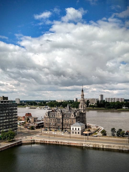 gray concrete building near body of water under white clouds and blue sky during daytime in Museum aan de Stroom Belgium