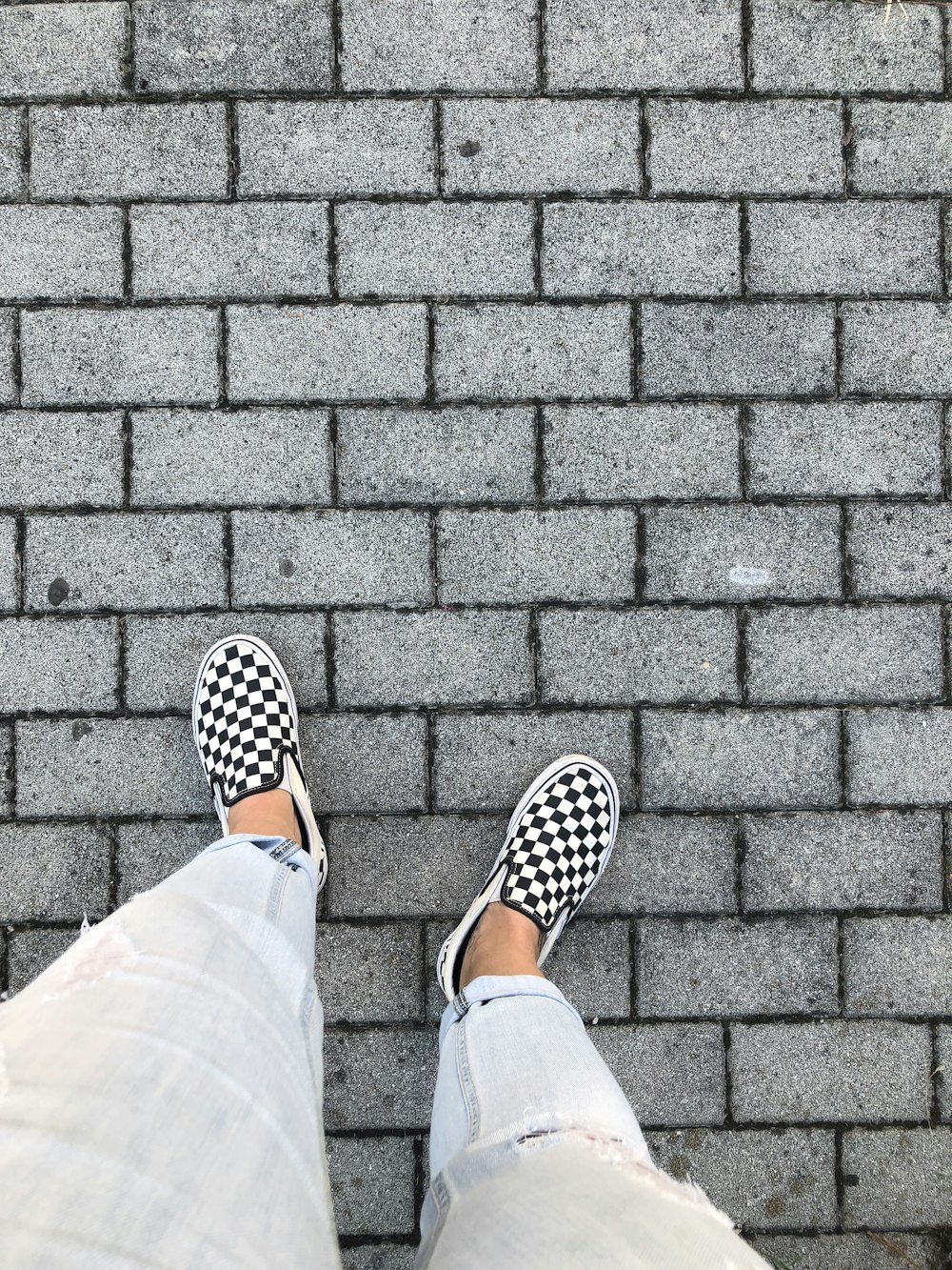 person in blue denim jeans and black and white polka dot slip on shoes