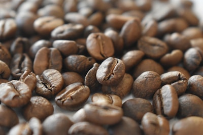 A close-up of coffee beans scattered on a textured surface, highlighting their rich color and texture.