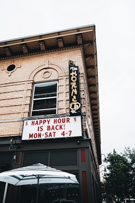 A corner view of a brick building featuring a classic marquee sign with neon lettering displaying 