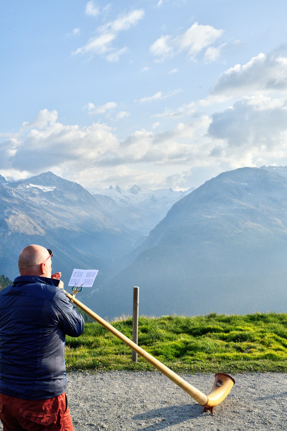 Hombre en chaqueta negra sentado en palo de madera marrón mirando las montañas durante el día