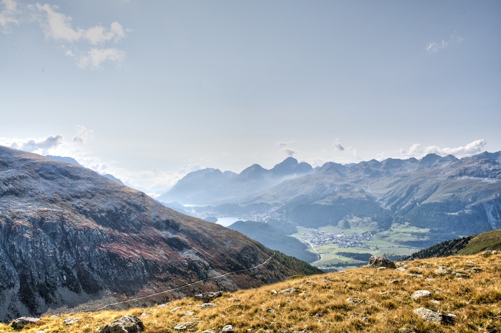 green grass field near mountains under white clouds during daytime