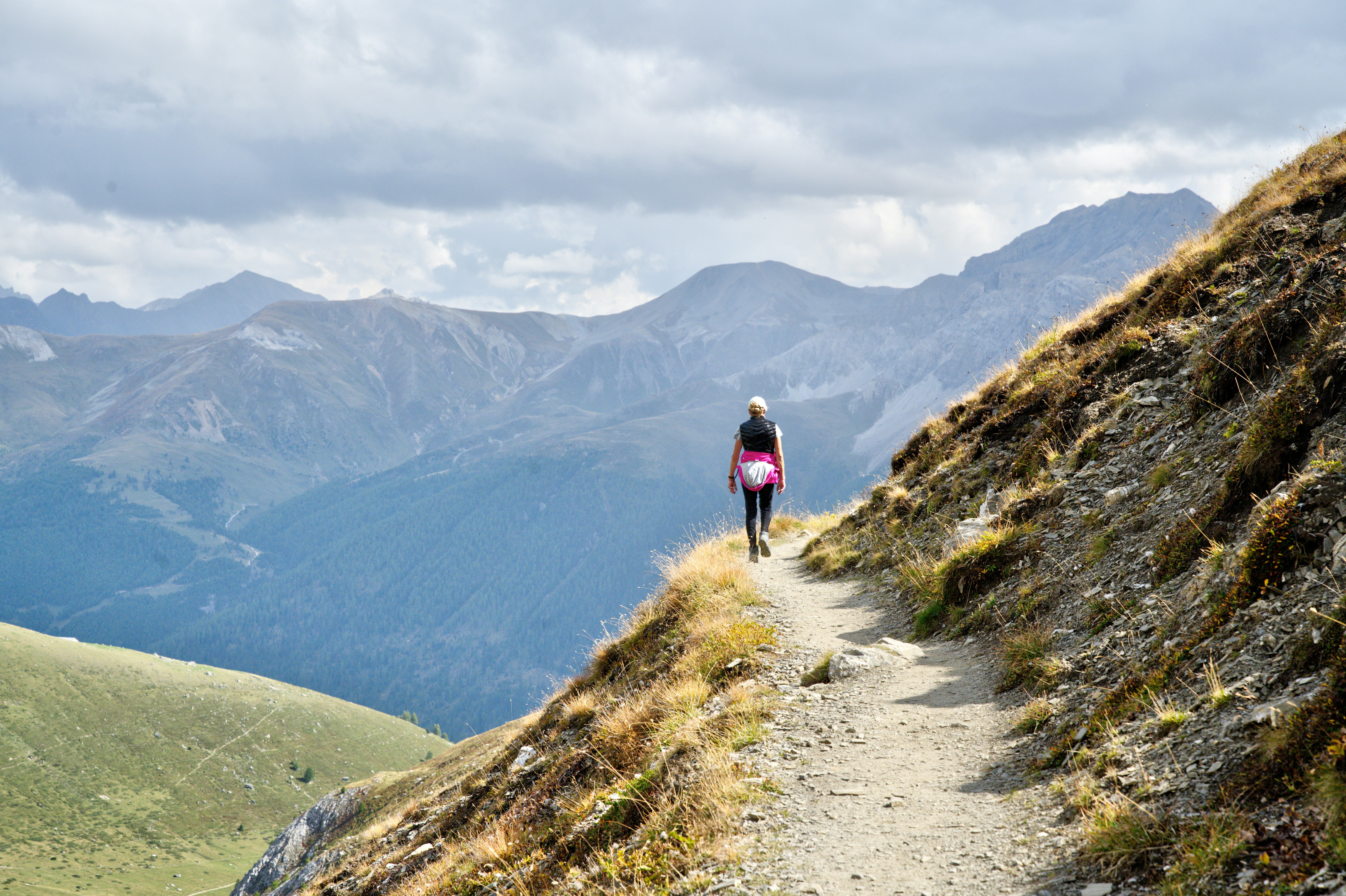 man in black jacket walking on gray dirt road during daytime