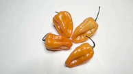 Bright orange habanero wing sauce with visible chili flakes in a rustic jar.