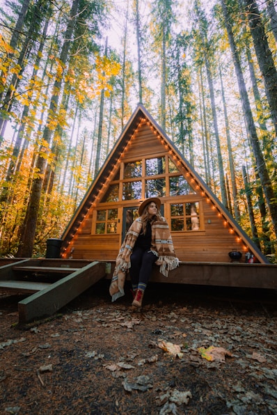 woman in brown coat standing on brown wooden bridge