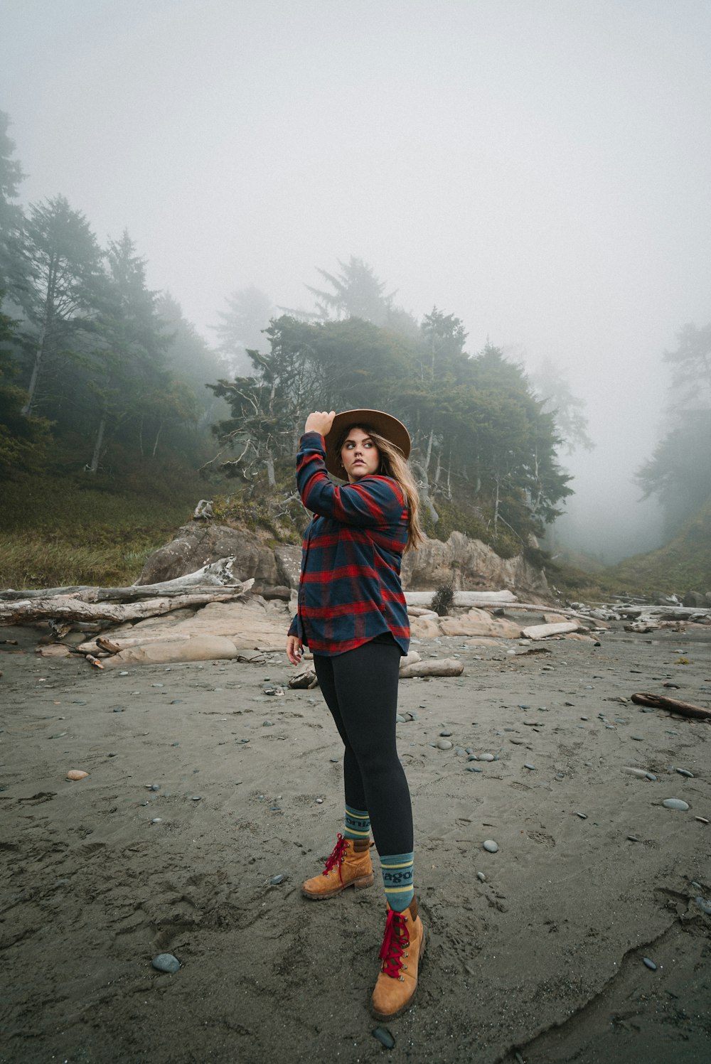 woman in red and blue plaid scarf standing on brown sand near green trees during daytime