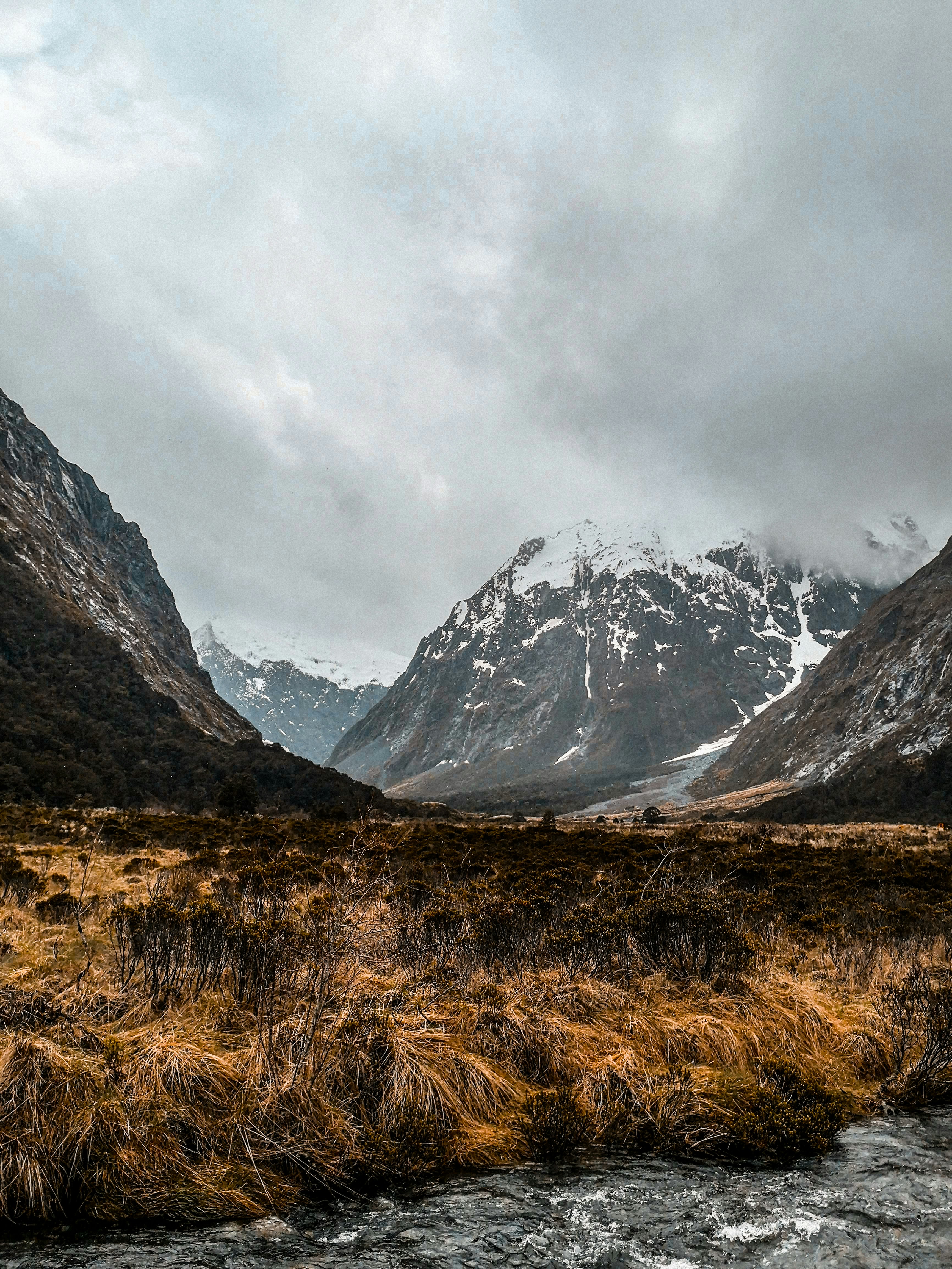 brown grass field near snow covered mountain during daytime