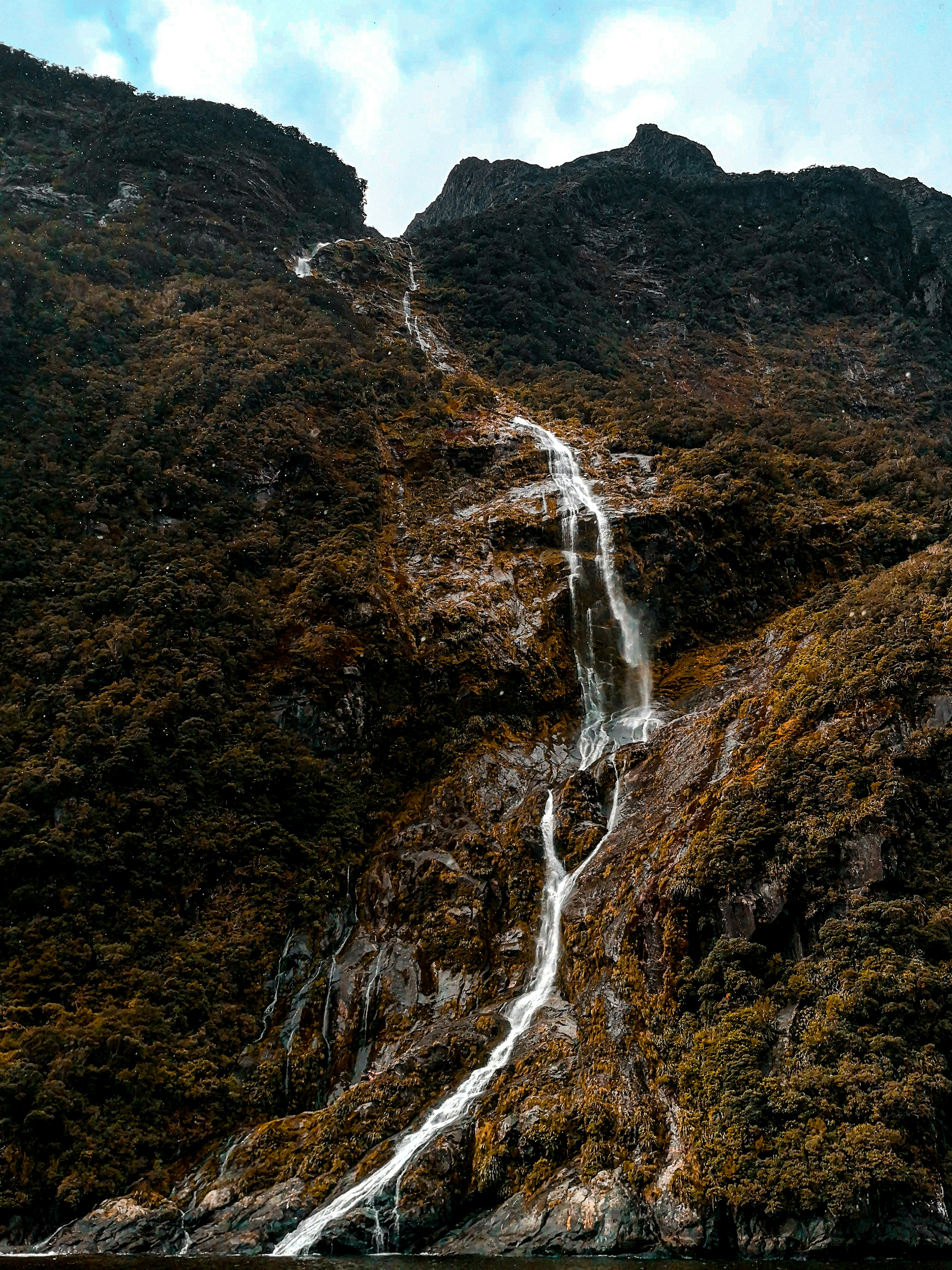waterfalls on brown rocky mountain during daytime