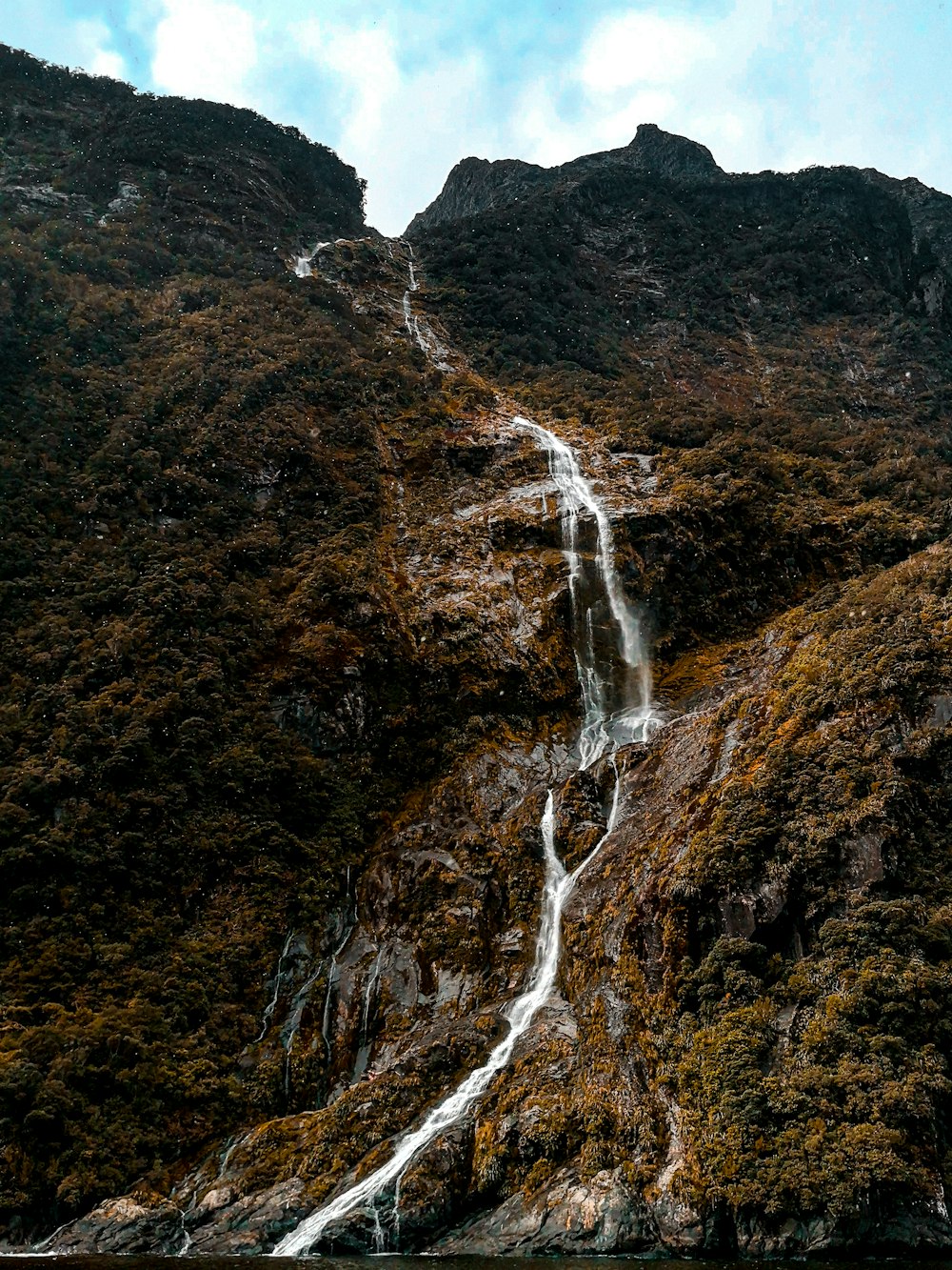 waterfalls on brown rocky mountain during daytime