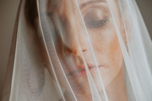 Close-up of a delicate bridal veil softly lit by natural sunlight filtering through a linen curtain.
