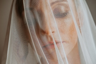 Close-up of a delicate bridal veil softly lit by natural sunlight filtering through a linen curtain.