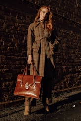 woman in brown coat holding brown leather handbag