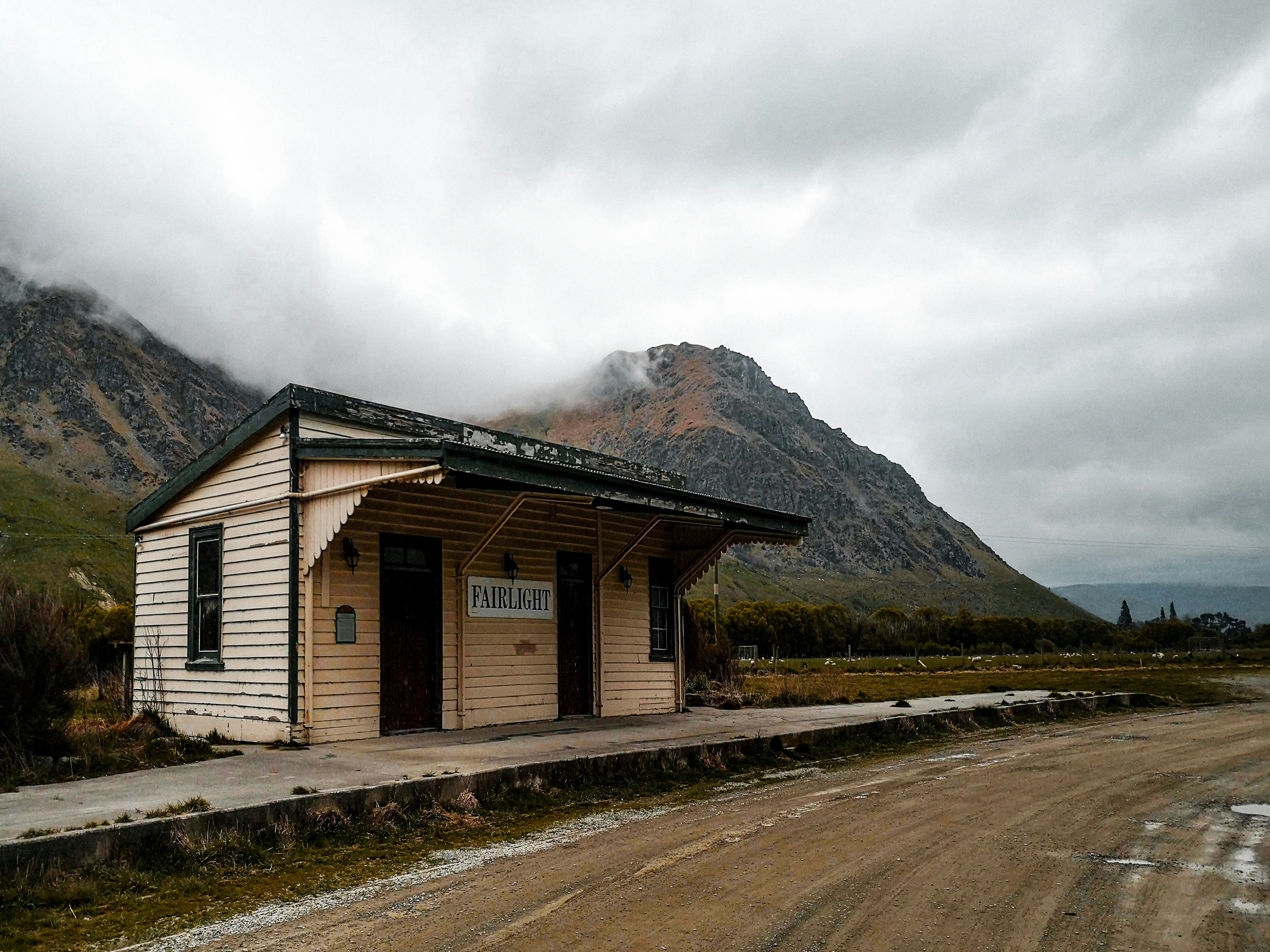 weißes und braunes Holzhaus in Bergnähe tagsüber unter weißen Wolken