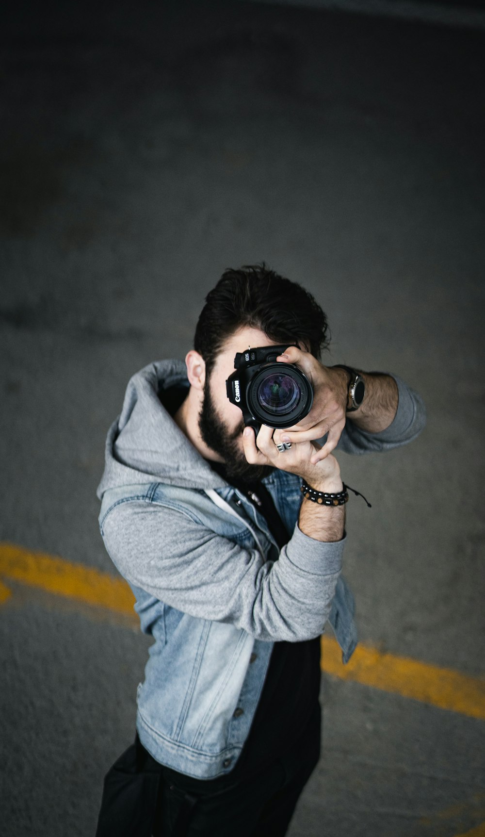 Mann in grauem Kapuzenpullover mit schwarzer DSLR-Kamera