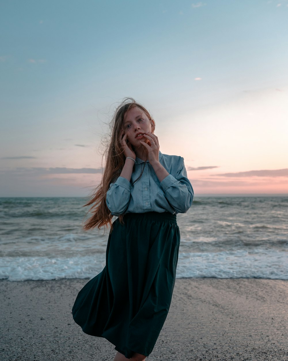 donna in camicia grigia a maniche lunghe in piedi sulla spiaggia durante il giorno
