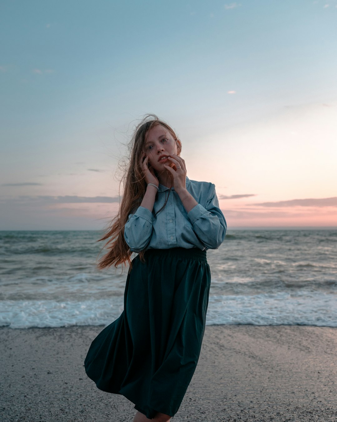 woman in gray long sleeve shirt standing on beach during daytime