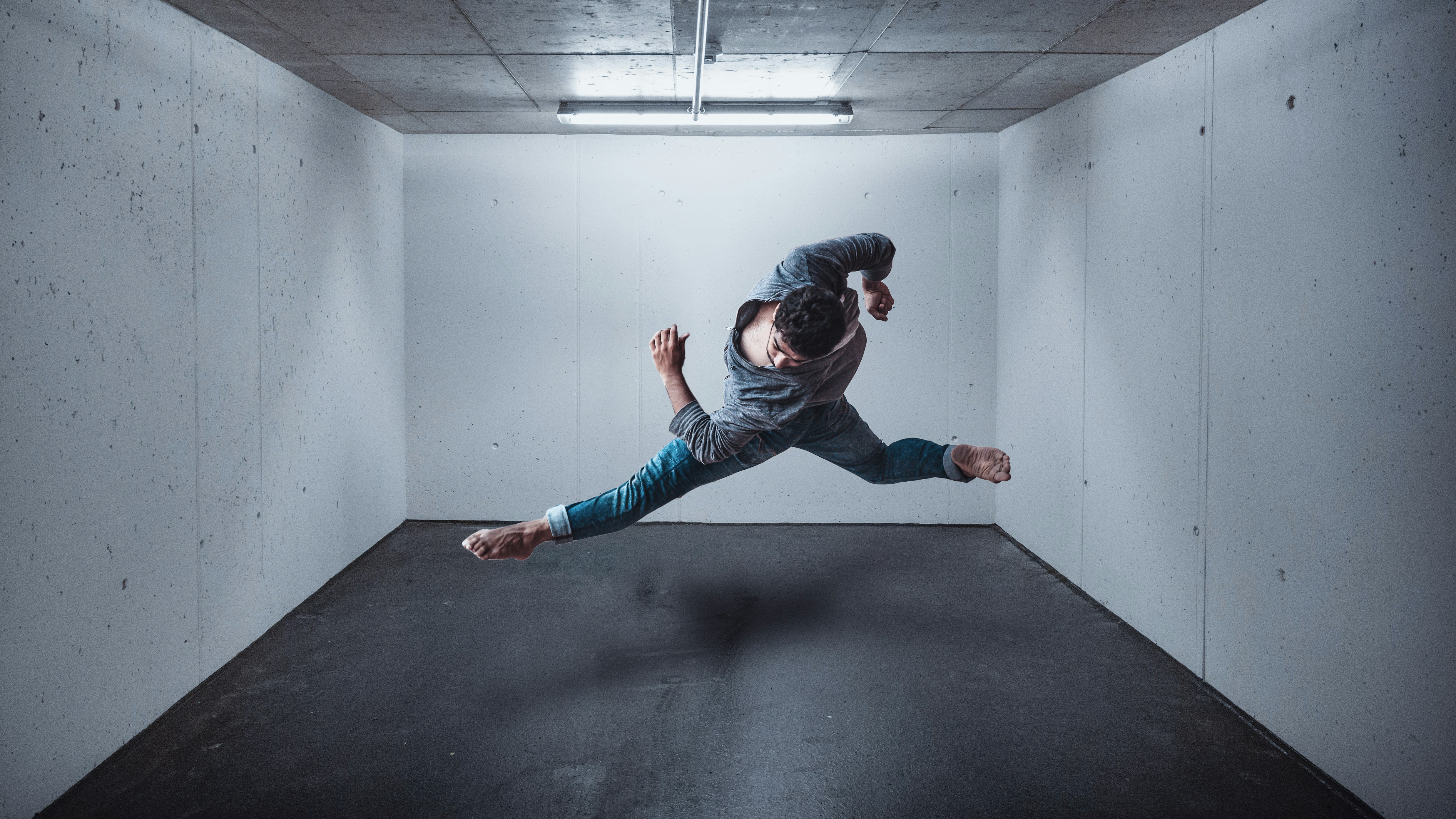 girl in blue denim jeans and black jacket jumping on black floor attractive teams background