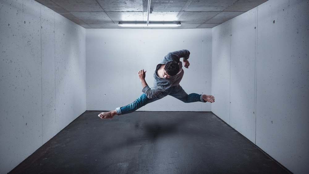 girl in blue denim jeans and black jacket jumping on black floor