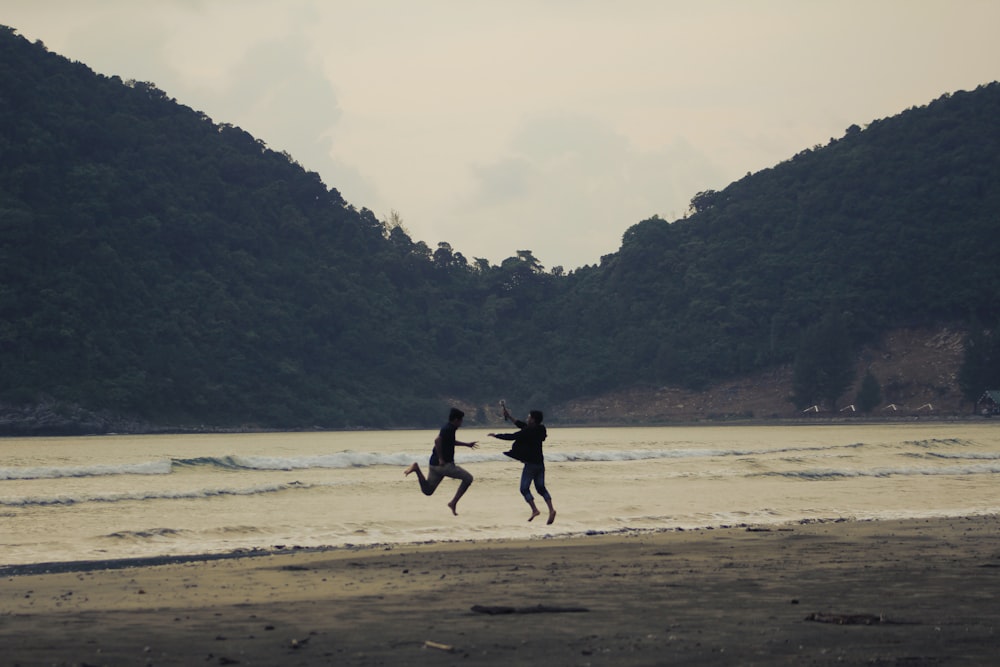 2 men running on beach during daytime