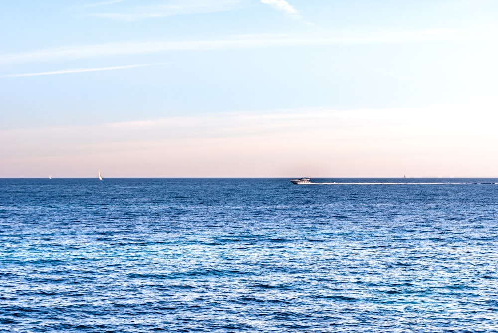 white boat on sea under white clouds during daytime