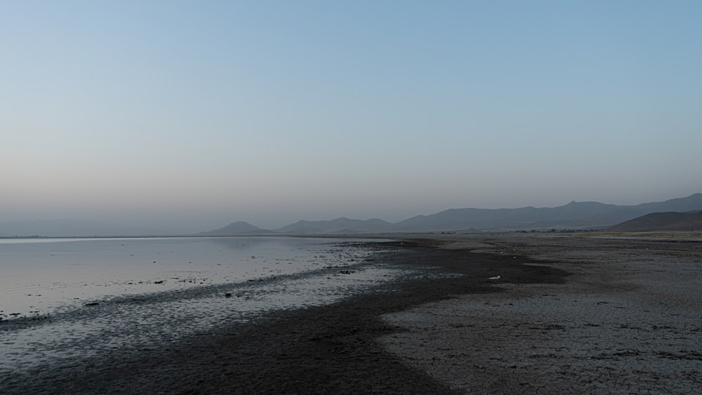 body of water near mountain during daytime