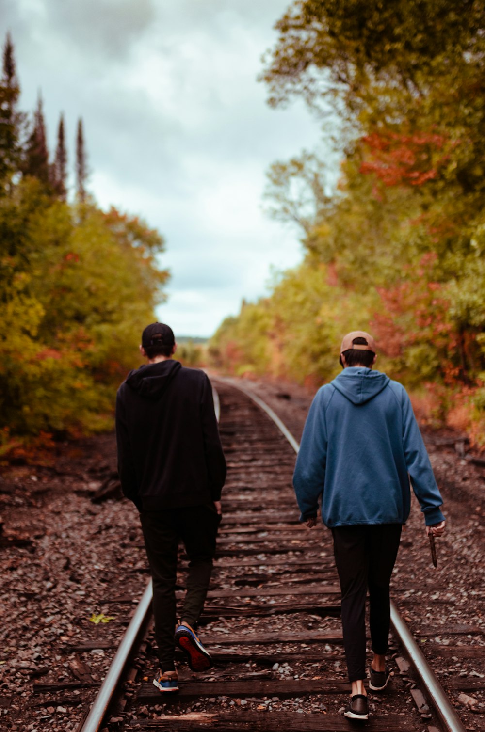 man in gray hoodie walking on pathway during daytime